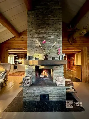 a stone fireplace with a clock in a living room at Log cabin in Hafjell with ski in ski out, sauna and view in Hafjell