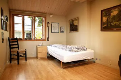a bedroom with a bed and a chair and a window at Villa Paradiso, Cathedral View & Parking in Trondheim