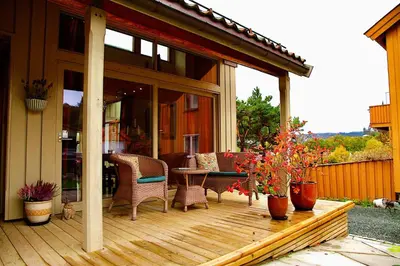 a patio with chairs and a table on a deck at Villa Paradiso, Cathedral View & Parking in Trondheim