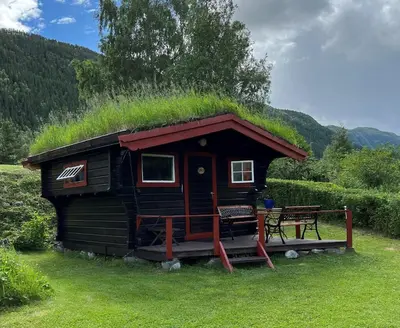 a small cabin with a grass roof with a bench at Kvila Hytteutleie in Garmo