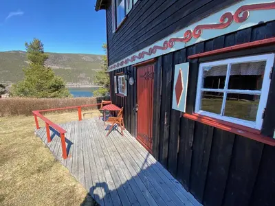 a wooden deck with a table and chairs on a house at Kvila Hytteutleie in Garmo