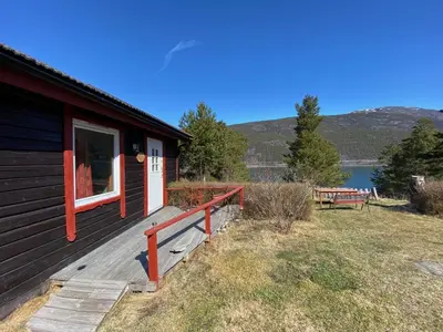 a cabin with a porch and a bench on the side at Kvila Hytteutleie in Garmo
