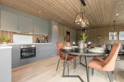 a kitchen and dining room with a table and chairs at Moderne hytte på Fjellsætra med Jacuzzi in Sykkylven