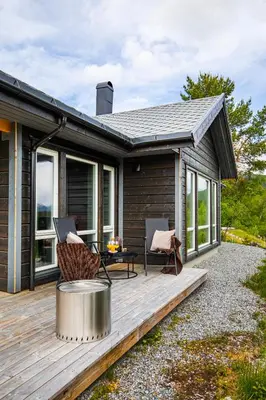 a wooden deck with a table and chairs on it at Moderne hytte på Fjellsætra med Jacuzzi in Sykkylven