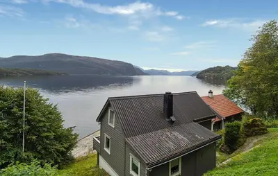 a house on a hill next to a body of water at 3 Bedroom Stunning Home In Omastrand in Sanddal