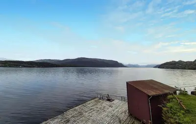 a dock on a lake with mountains in the background at 3 Bedroom Stunning Home In Omastrand in Sanddal
