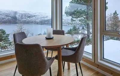 a table with chairs and a candle in a room with windows at 2 Bedroom Lovely Home In Bjordal in Hogvær