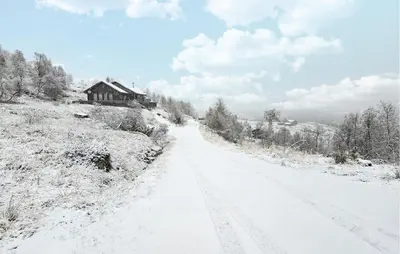 a road covered in snow with a house in the background at 2 Bedroom Lovely Home In Bjordal in Hogvær