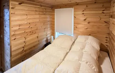 a bedroom with a bed in a wooden wall at 2 Bedroom Lovely Home In Bjordal in Hogvær