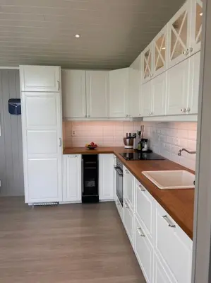 a kitchen with white cabinets and a counter top at Hytte v Farstadsanden Anders sandvigsvei 9 in Julshamn
