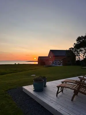 a wooden deck with a bench and a table and a sunset at Hytte v Farstadsanden Anders sandvigsvei 9 in Julshamn