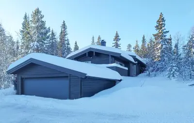 a building covered in snow with trees in the background at Stunning Home In Trysil With Sauna in Trysil