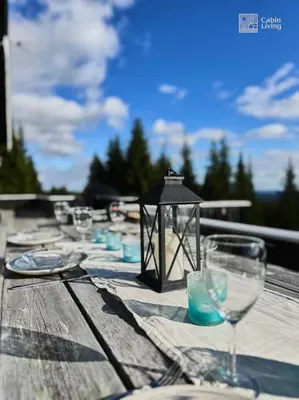 a wooden table with wine glasses and a lantern at Luxury cabin Sjusjøen with hot tub, ski in-out, fireplace & WiFi in Ringsaker