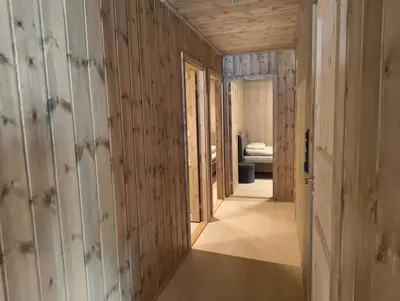 a hallway with wooden walls and a room with a bed at OlaHytta - Cozy cabin close to kvitfjell in Tromsnes