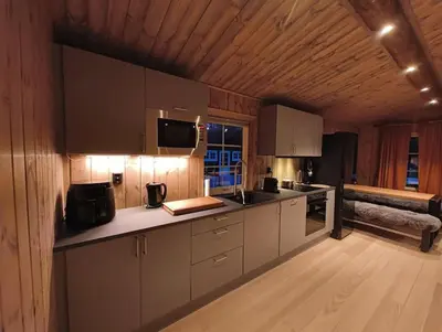 a kitchen with white cabinets and a wooden ceiling at OlaHytta - Cozy cabin close to kvitfjell in Tromsnes