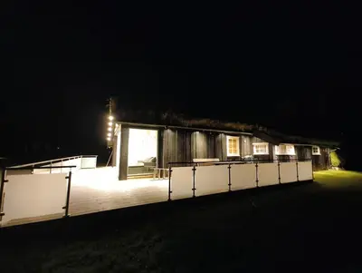 a house lit up at night with a deck at OlaHytta - Cozy cabin close to kvitfjell in Tromsnes