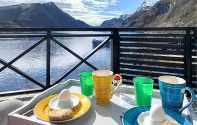 a table with plates of food and cups on a balcony at 4 Bedroom Nice Home In Deknepollen in Måløy