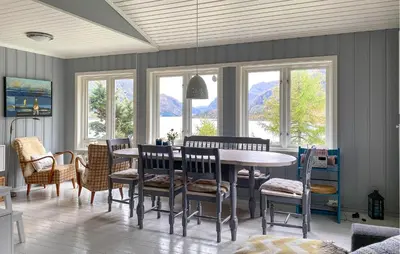 a dining room with a table and chairs and windows at 4 Bedroom Nice Home In Deknepollen in Måløy