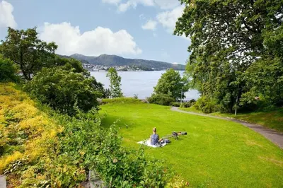 a woman sitting in the grass with two dogs at Cozy studio in Bergen center in Bergen
