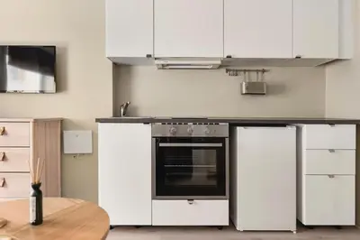 a kitchen with white cabinets and an oven and a table at Cozy studio in Bergen center in Bergen