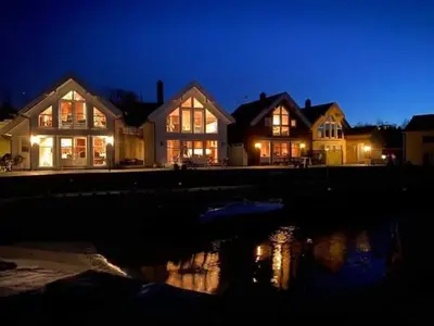 a large house at night with the lights on at Moderne Rorbu helt i sjøkanten in Hauge