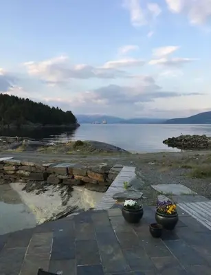 two pots of flowers sitting on a stone path near the water at Moderne Rorbu helt i sjøkanten in Hauge