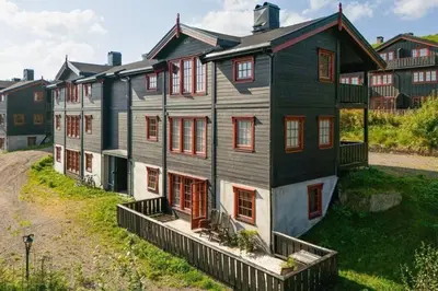 a large house with red shutters on a street at Leilighet sentralt i Trysil in Hovi