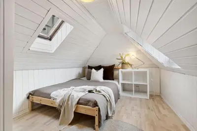 a white attic bedroom with a bed and a window at Historisk hus i hjertet av byen in Bergen