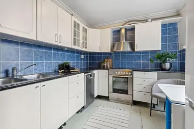 a kitchen with white cabinets and blue tiles at Historisk hus i hjertet av byen in Bergen