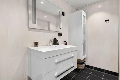 a white bathroom with a sink and a mirror at Trolltunga Fjord View in Tokheim