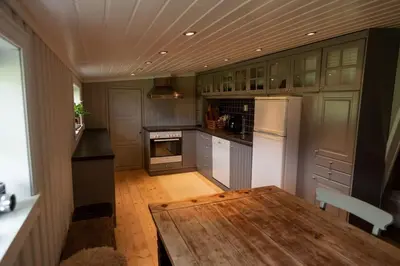 a kitchen with a wooden table and a white refrigerator at Cozy apartment close to the ski resort in Oppdal