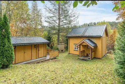 two wooden buildings in a yard with trees at Rindalsskogen cabin in Løfald