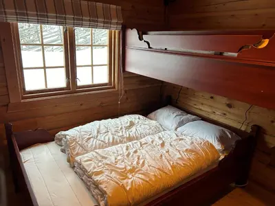 a bed in a wooden room with two windows at Perfectly Located Timber Cabin For 6-8 Guests in Beitostøl