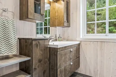 a bathroom with wooden cabinets and a sink and a window at Tenden Panorama in Stryn