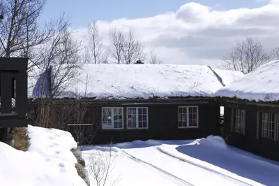a house with snow on top of its roof at Koselig Sentral Eldre Hytte Med Peis in Beitostøl