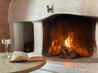 an open book and a glass of wine next to a fireplace at Koselig Sentral Eldre Hytte Med Peis in Beitostøl