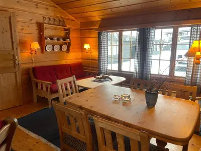 a dining room with a wooden table and chairs at Koselig Sentral Eldre Hytte Med Peis in Beitostøl