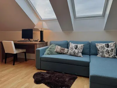 a living room with a blue couch and a desk at Beautiful penthouse centrally located in Geilo, stunning views in Geilo