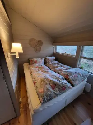 a bed in a small room with a window at Cabin on an beautiful island with a sea view in Vinsternes