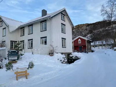 a white house with a red barn in the snow at Ner-Grefstad gard in Kallstad