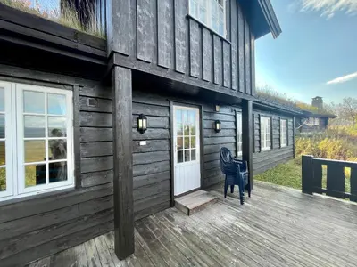 a wooden house with a blue chair on a deck at Charming Family Cabin With Stunning Mountain Views in Beitostøl