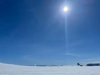 a sun shining in the sky over a snow covered field at Charming Family Cabin With Stunning Mountain Views in Beitostøl