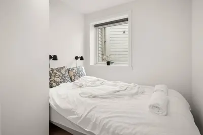 a white bed in a white room with a window at Bergen City Center Bryggen in Bergen