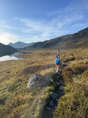 a woman walking down a trail on a hill at Modern Retreat By Beitostølen Ski Stadium in Beitostøl