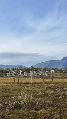 a sign in a field with mountains in the background at Modern Retreat By Beitostølen Ski Stadium in Beitostøl