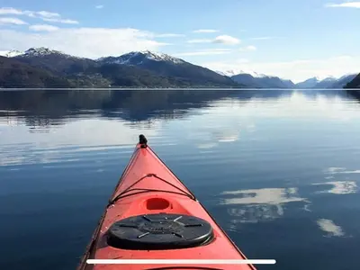 a red kayak on a body of water with mountains at 12 person holiday home in Davik in Davik