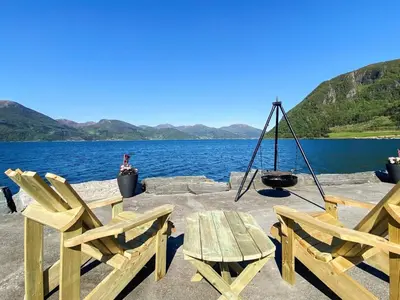 a picnic table and two chairs next to a lake at 12 person holiday home in Davik in Davik