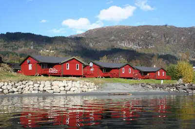 a row of red houses next to a body of water at Sauda Fjord Camping in Saudasjøen