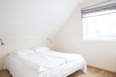a white bed in a white room with a window at Sauda Fjord Camping in Saudasjøen