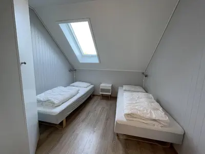 two beds in a small room with a window at Sauda Fjord Camping in Saudasjøen